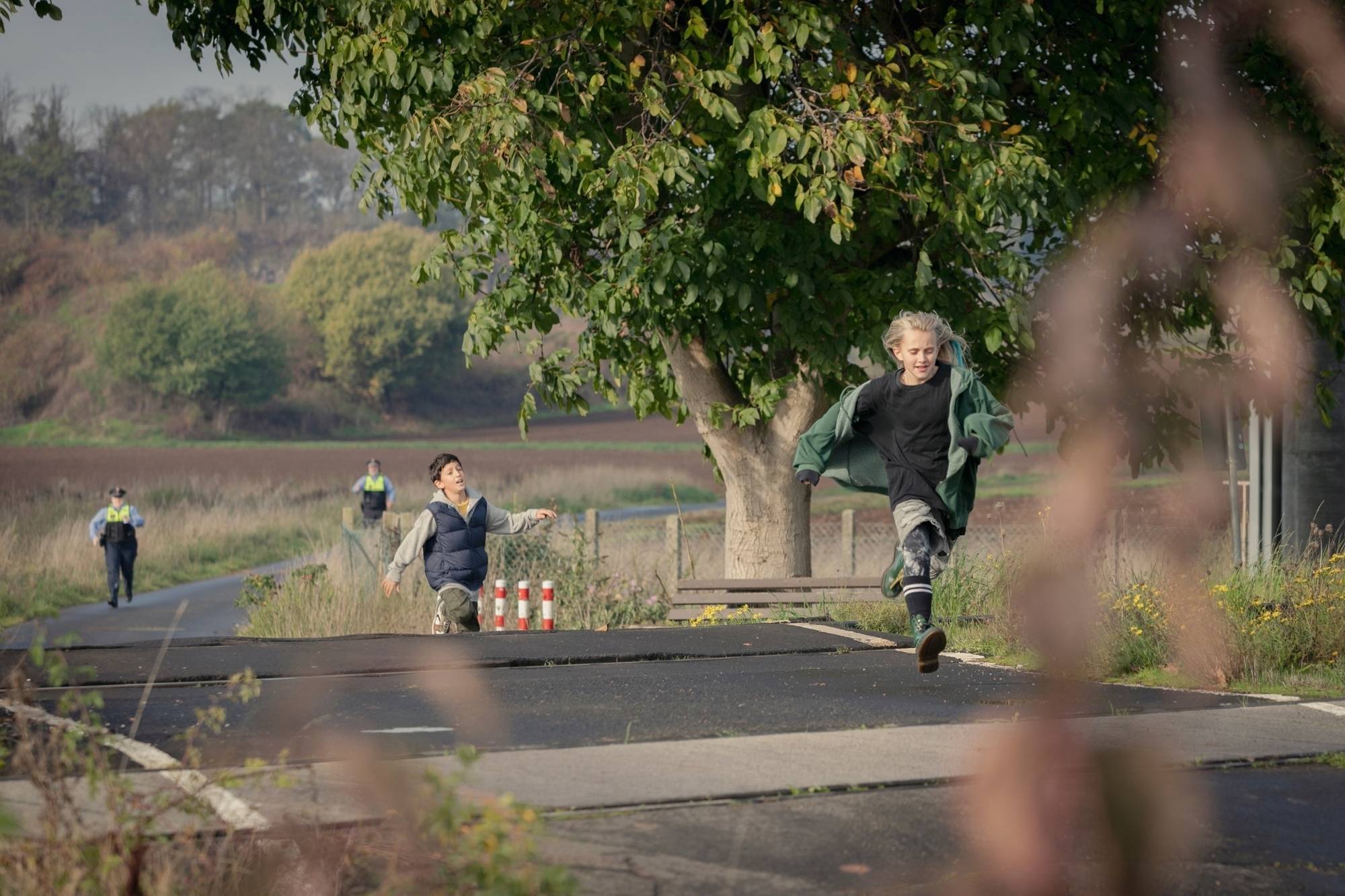 Finn und Jola are being chased by two police officers on a country road.